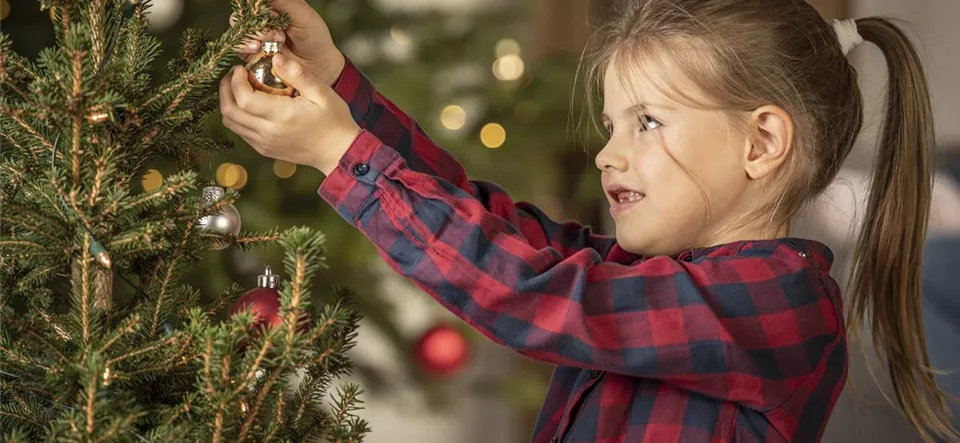 Mädchen schmückt Weihnachtsbaum